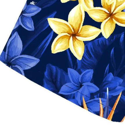 Uitsnede: blauwe bloemen en gele bloemen in een tropisch motief op donkerblauwe stof