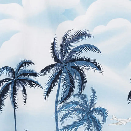 Kurzes Hawaiihemd mit Palmenprint, große Blattmotive vor wolkigem Himmel
