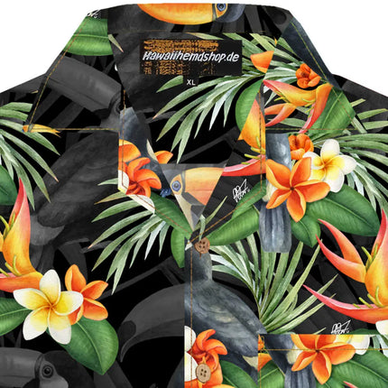 Dettaglio del tessuto: stampa tropicale nera con tucani, foglie di palma e fiori arancioni e bianchi